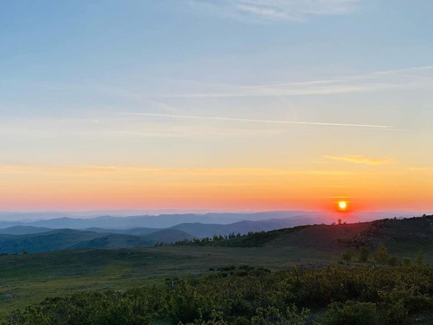 A sunrise over rolling green hills.