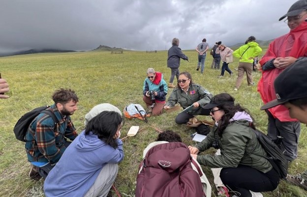 A group of people gathered outside studying vegetation.