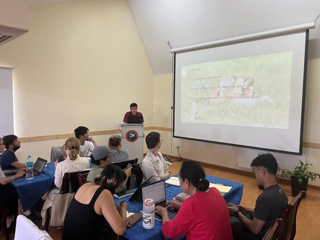 A group of participants in a classroom look at a powerpoint presentation discussing Mongolian marmots.