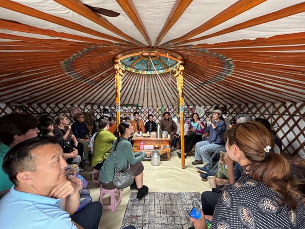 A group of people having a discussion sit inside a Mongolian ger.