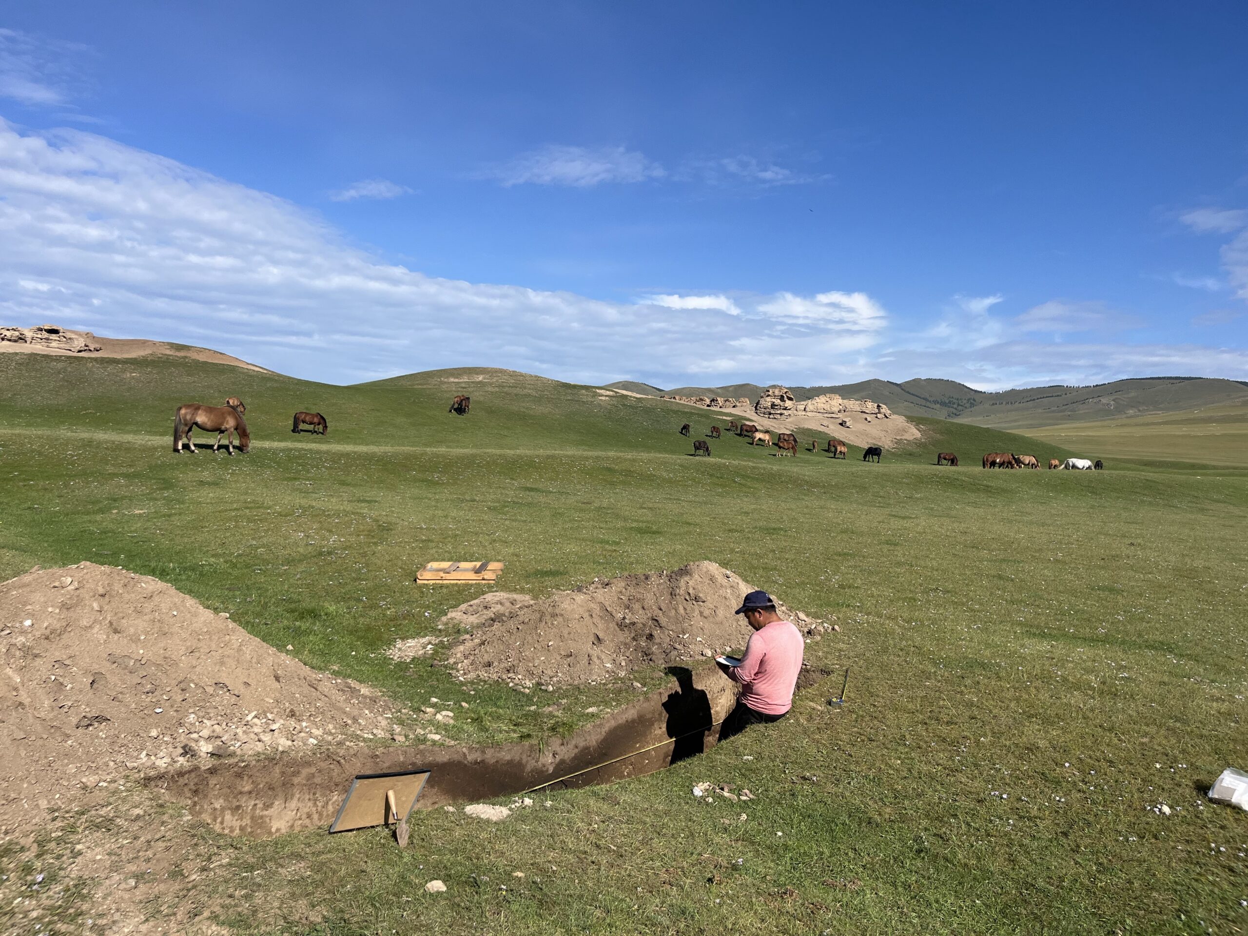 An archaeologist excavates at an outdoor site in Mongolia.