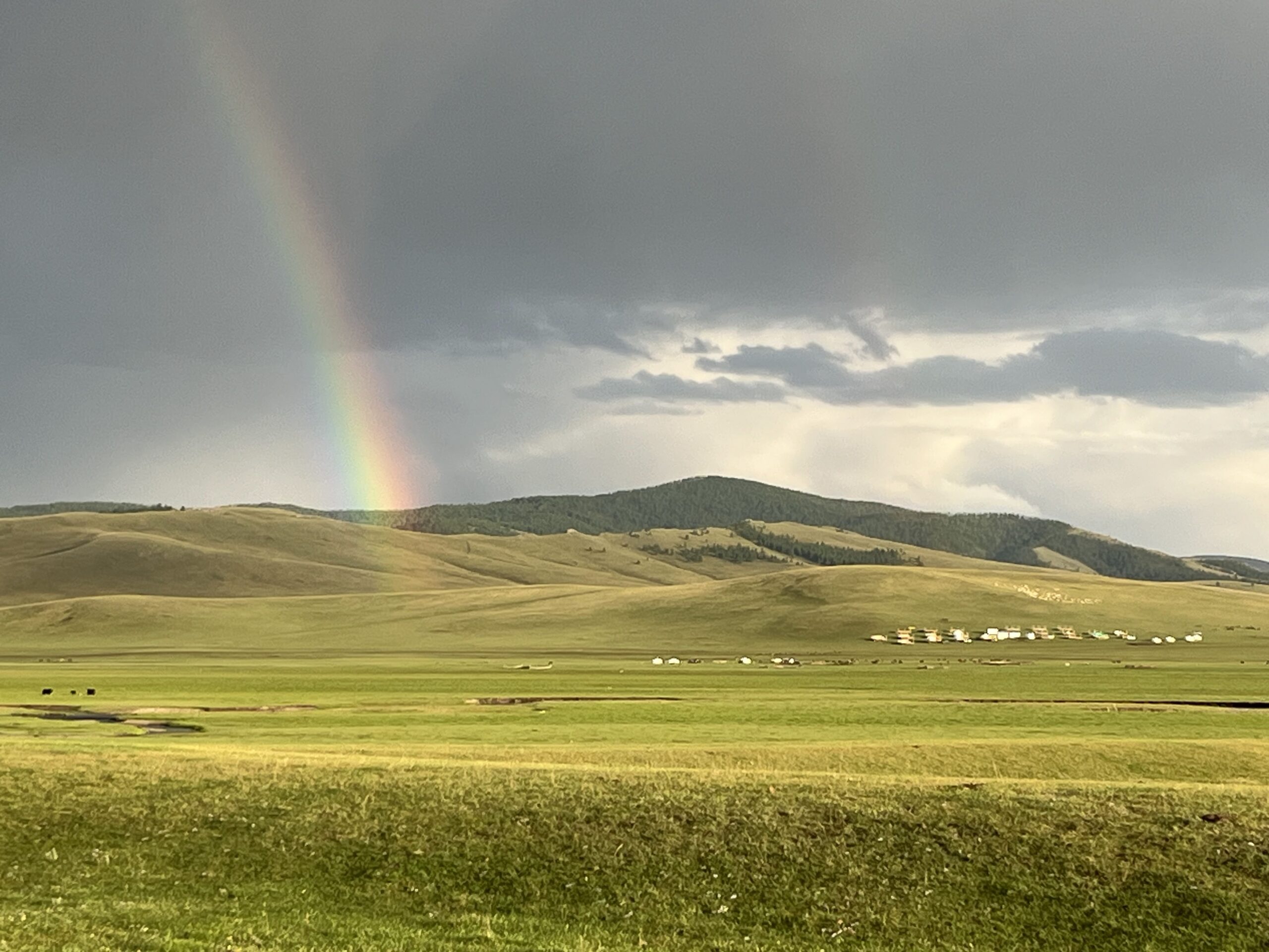 A photograph of the sprawling green step with a rainbow in the background.