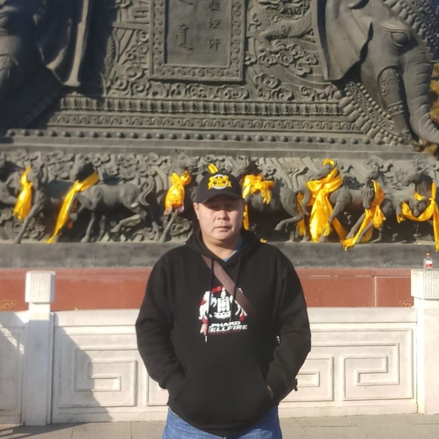 A photo of a man standing in front of a large bronze statue.